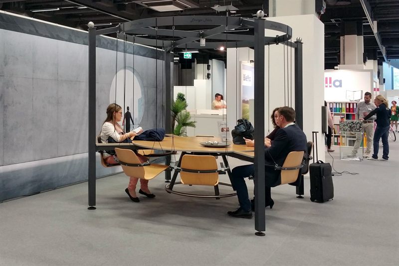 Messebesucher unterhalten sich auf den Schwingsitzen des LOUNGETABLE