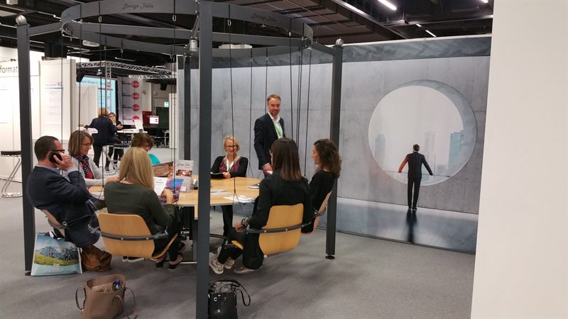 Voll besetzter LOUNGETABLE mit Gästen im Gespräch auf der Messe